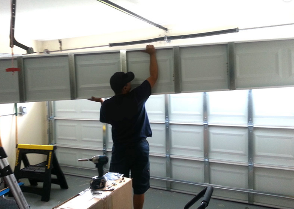 Image showing a technician performing garage door section replacement in Gahanna, Ohio, with tools and garage door panels visible.