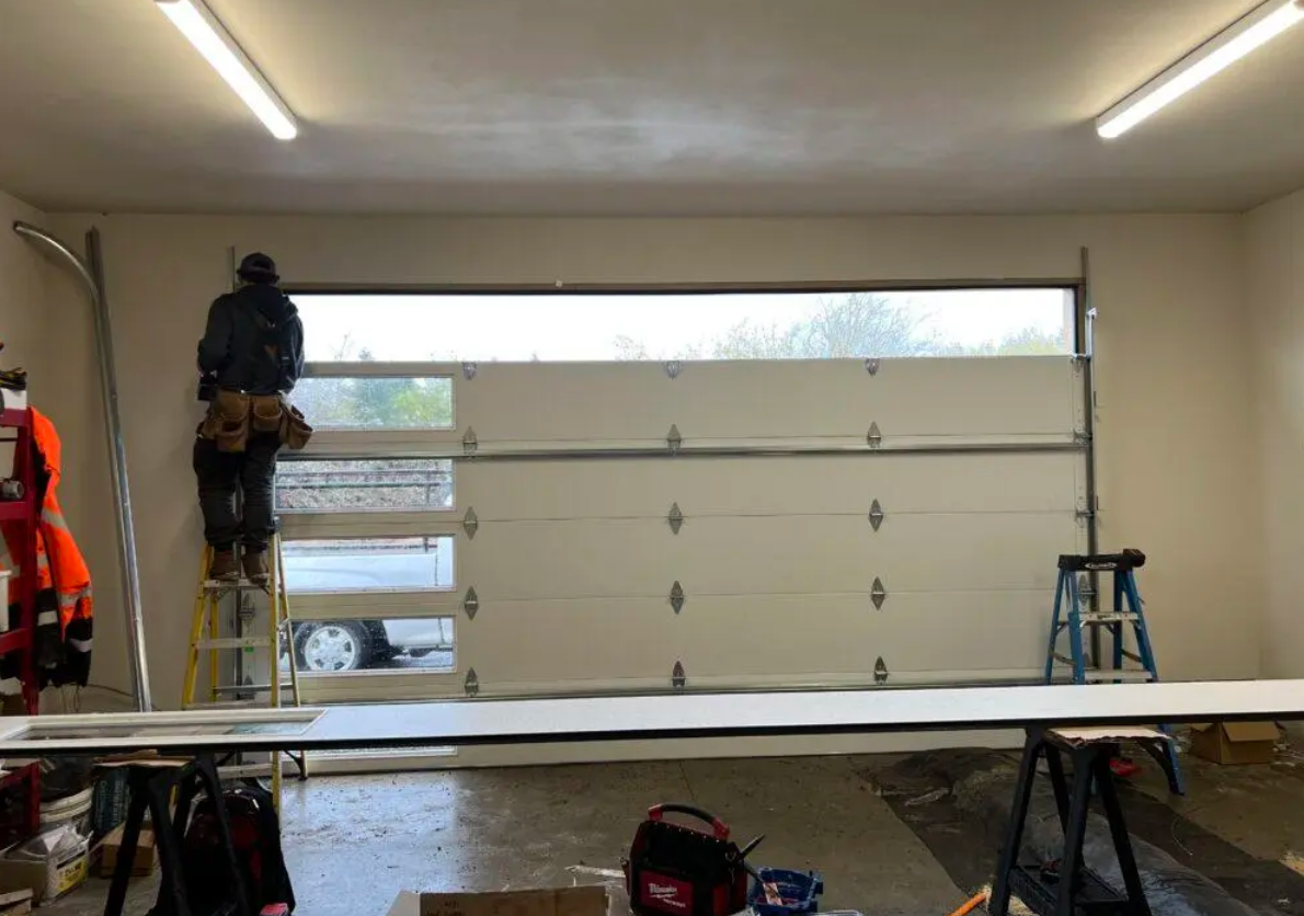 A professional technician performing garage door installation on a residential home in Gahanna, Ohio, with new panels and tools displayed.
