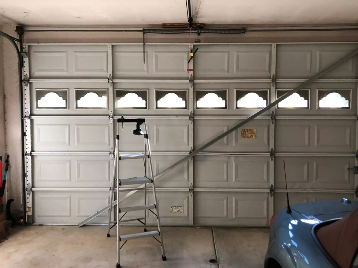 A professional technician performing same-day garage door repair on a residential garage in Gahanna, Ohio, with tools and a service vehicle visible.