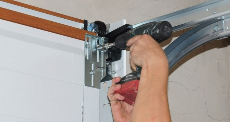 Technician performing a noisy garage door fix in Gahanna, Ohio, lubricating metal hinges and tracks for smooth operation.