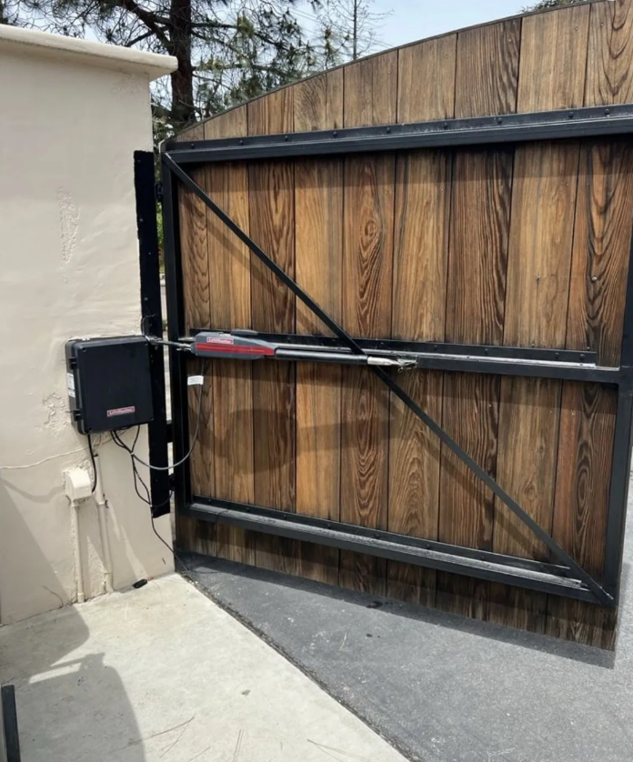 A garage technician is performing Automated Gate Systems in Gahanna, Ohio, with tools and a partially repaired driveway gate visible in the background.