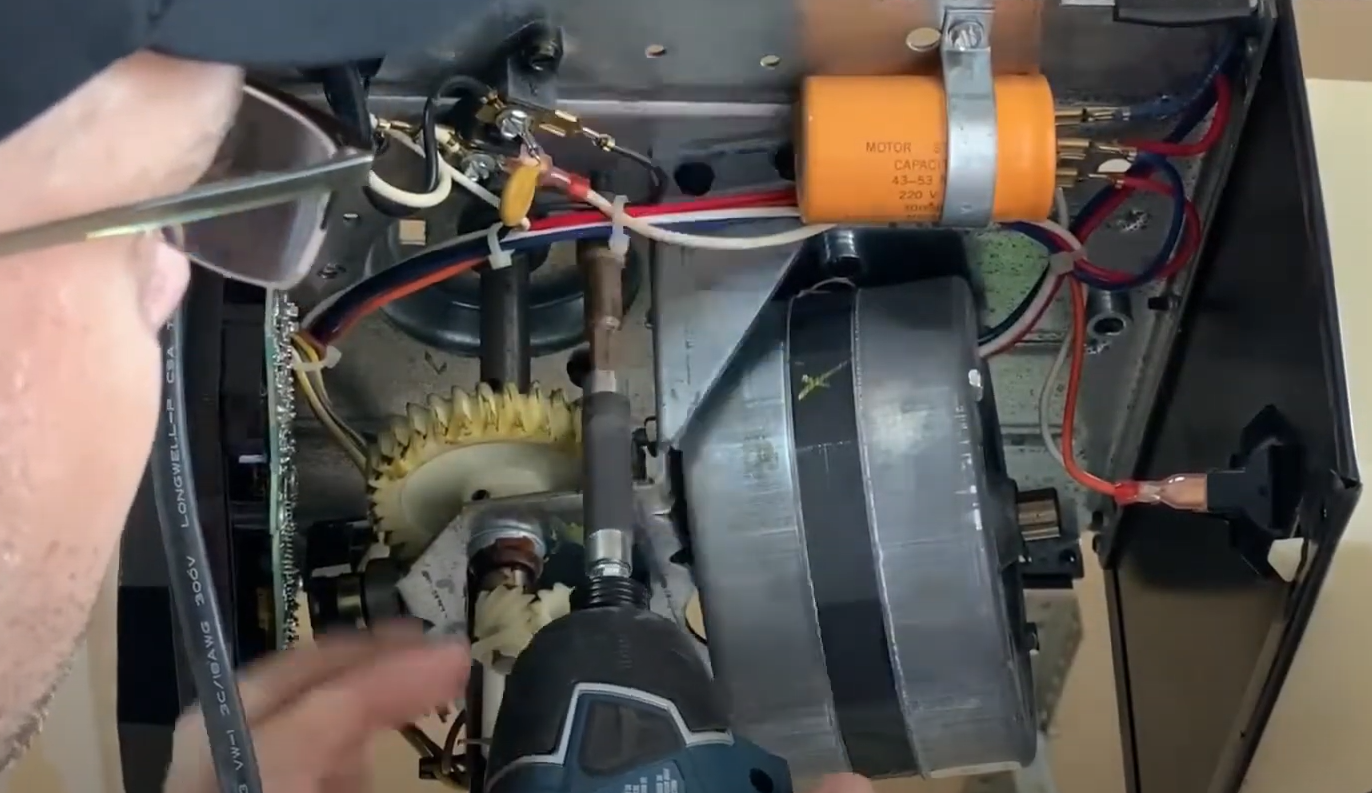 a professional technician fixing a residential garage door opener mechanism in Gahanna, Ohio. The technician is using specialized tools to ensure efficient garage door opener repair. The image highlights the expertise and quality service provided by Garage Door Repair Gahanna Ohio LLC.